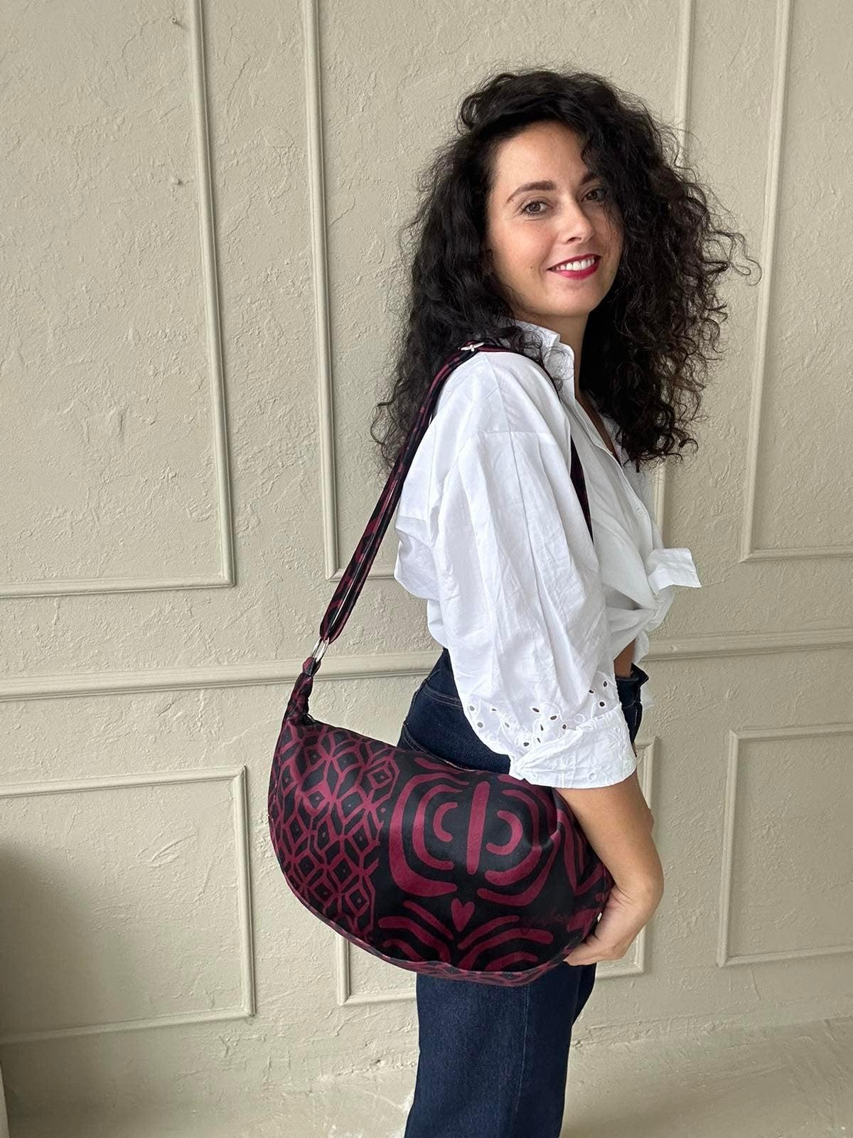 confident woman showcasing a chic burgundy velour hobo bag with an adjustable shoulder strap