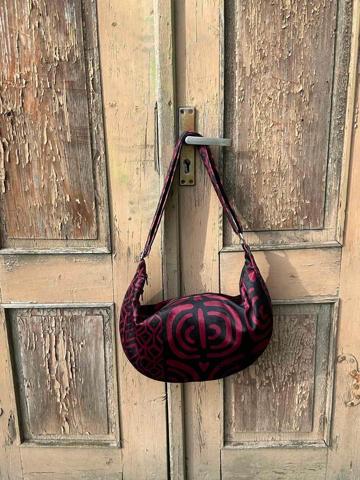 a practical view of the chic burgundy hobo bag with its adjustable strap extended to full length
