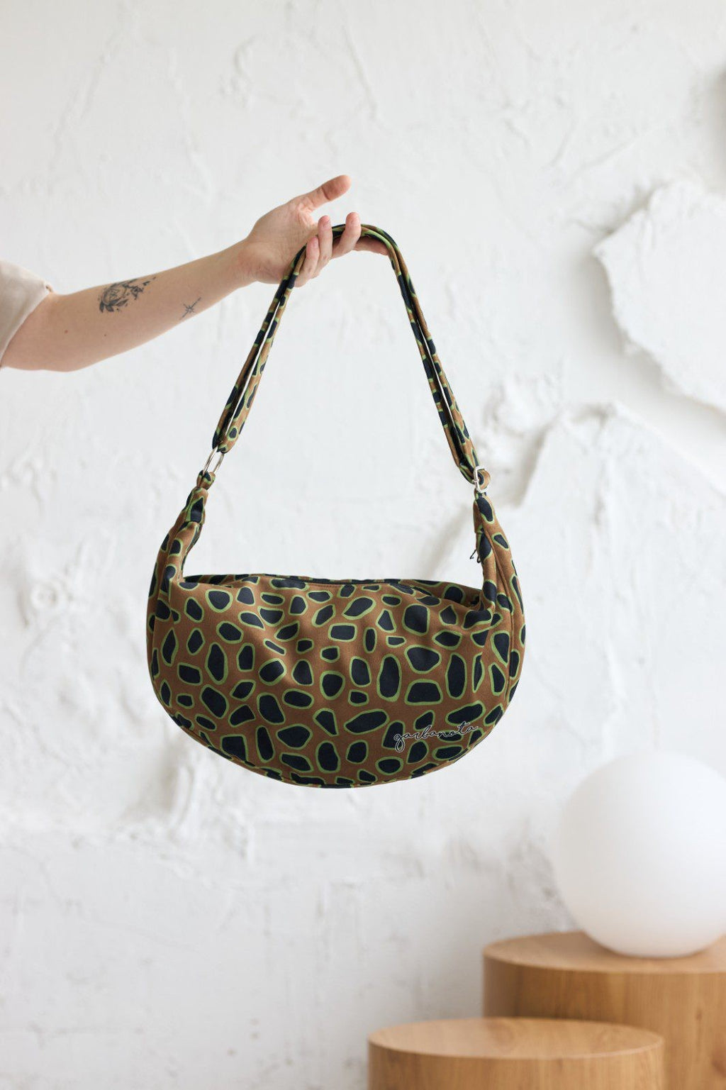 a soft velour curly leopard hobo bag held gently in warm, natural light
