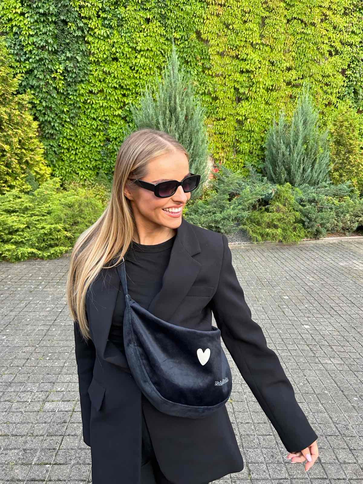 confident woman modeling a chic black velour hobo bag with a bold, slouchy silhouette