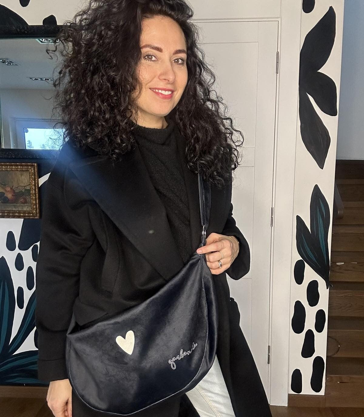 a playful shot of a chic black velour hobo bag being playfully swung by its adjustable strap