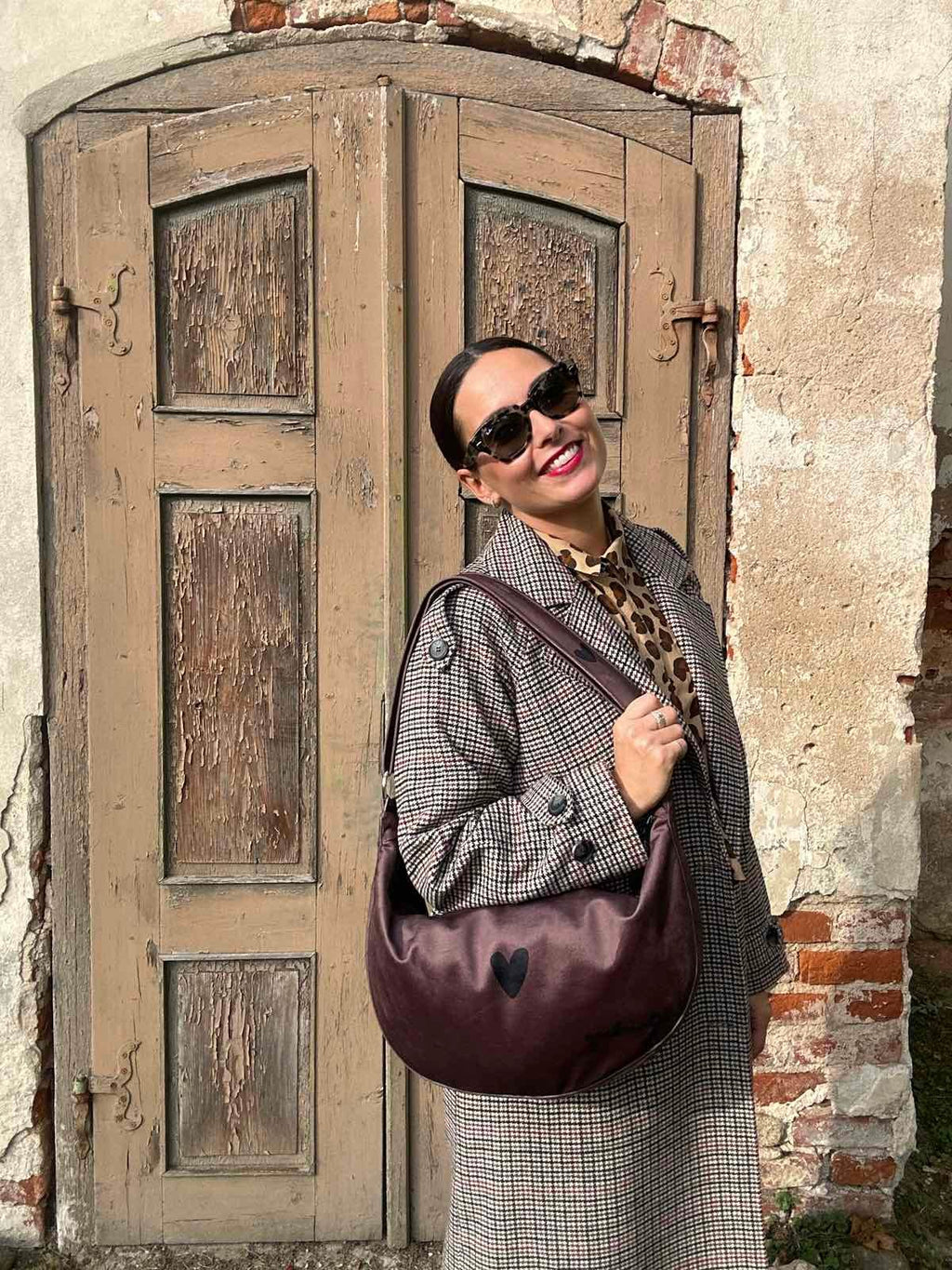 confident woman modeling a chic brown velour hobo bag with an adjustable shoulder strap