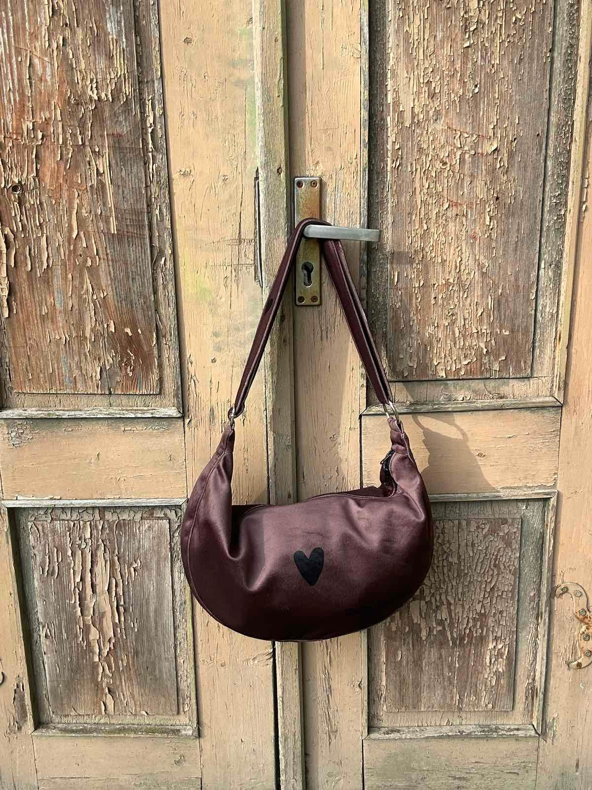 playful slouch of a brown velour hobo bag on a sunny park bench