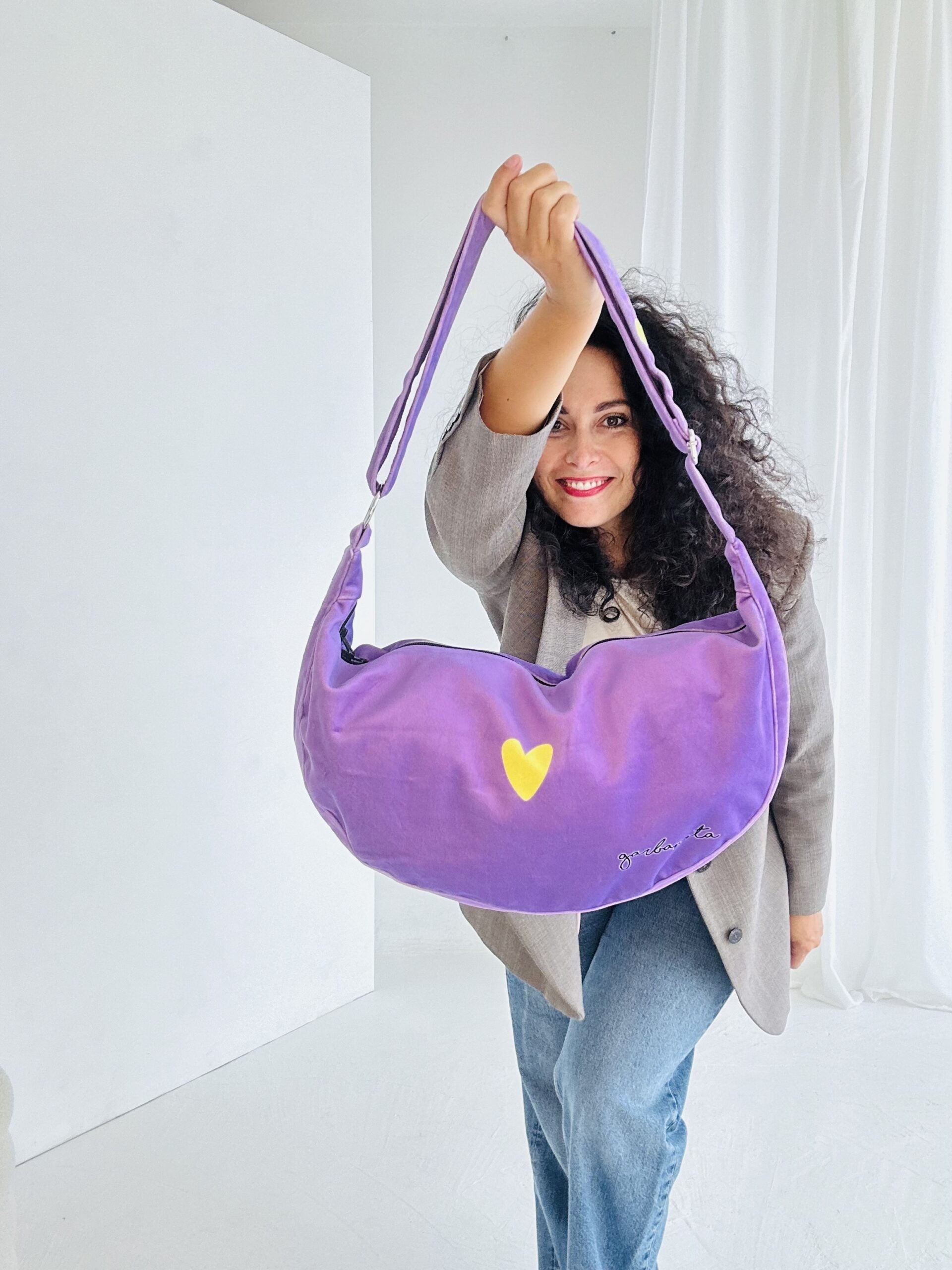 a bold close-up of a chic purple velour hobo bag with its adjustable strap extended