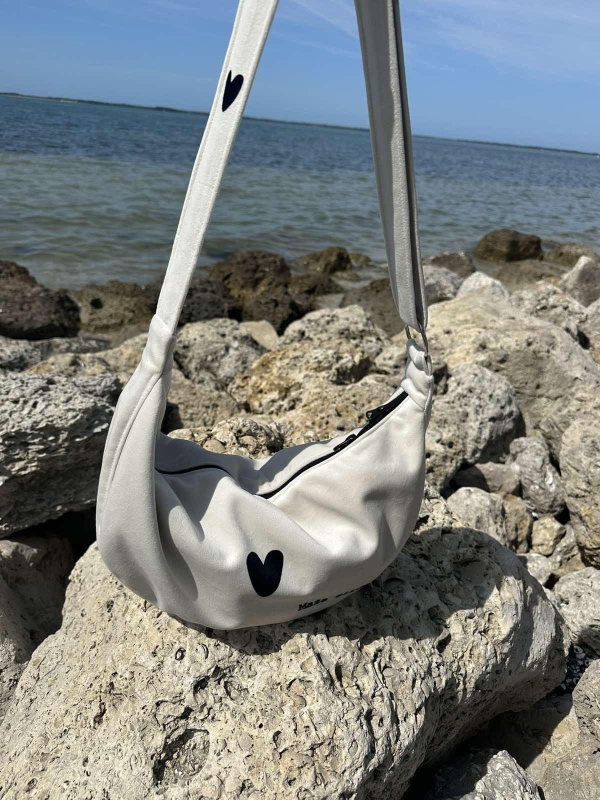 elegant white velour hobo bag with heart charm, shown from a functional angle highlighting its adjustable strap and interior pockets