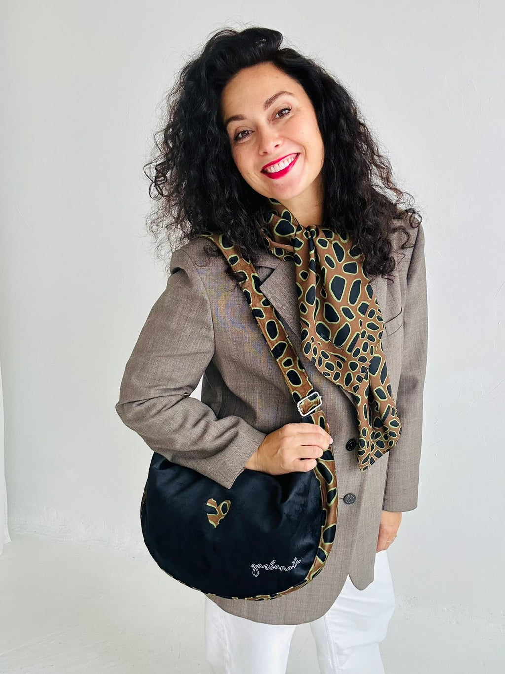 confident woman holding a bold leopard heart hobo bag against a dark background