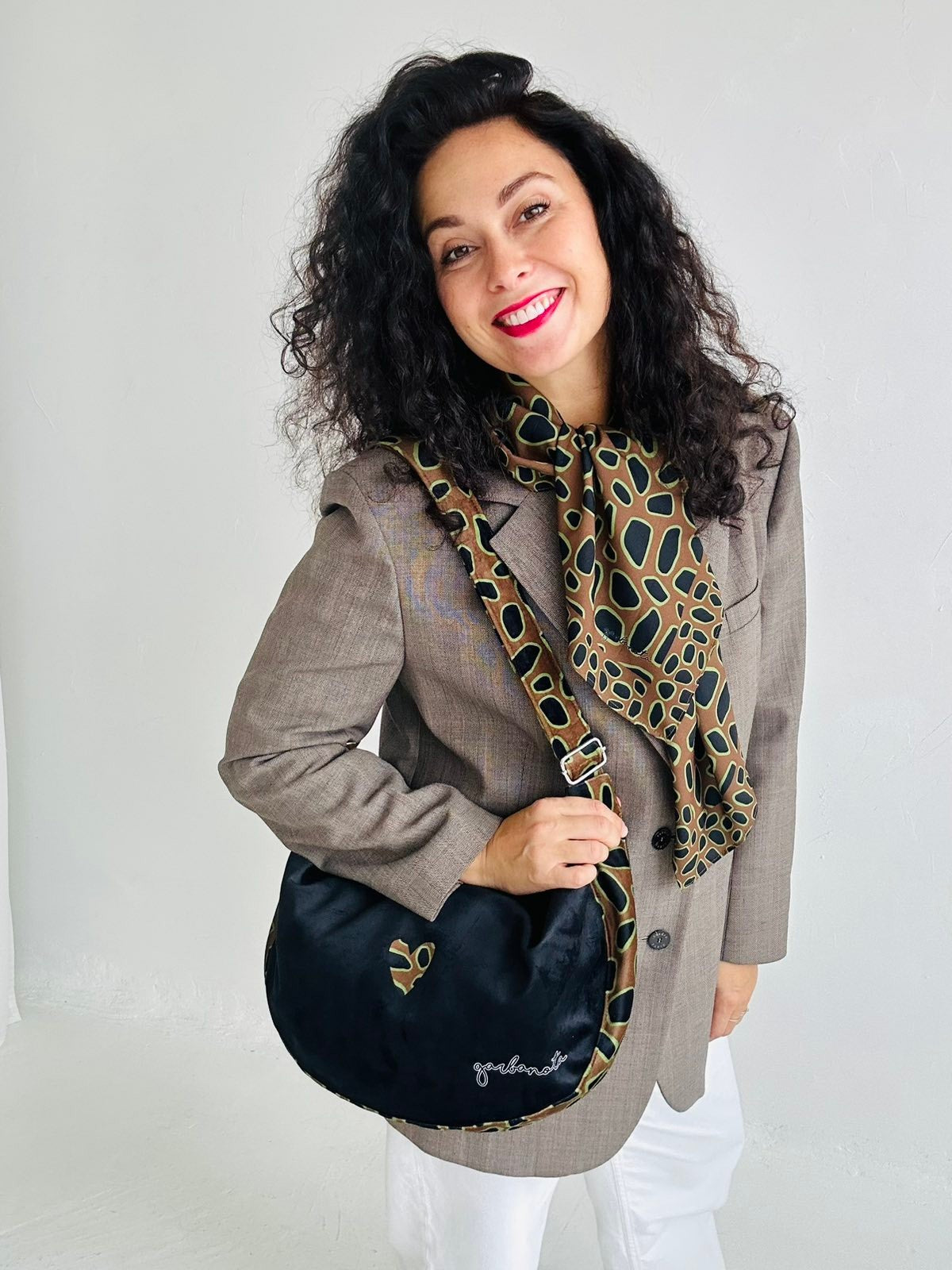 confident woman holding a bold leopard heart hobo bag against a dark background