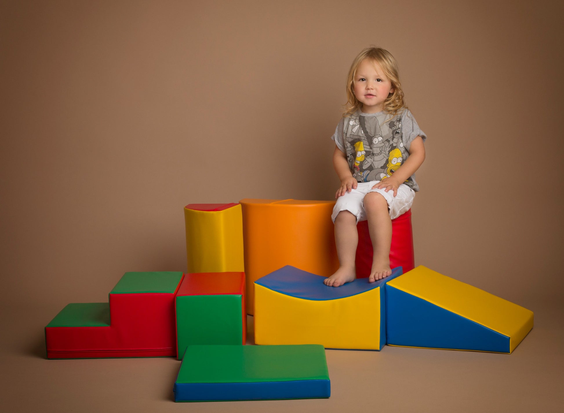 a toddler laughing while building a colorful iglu soft block tower during playtime
