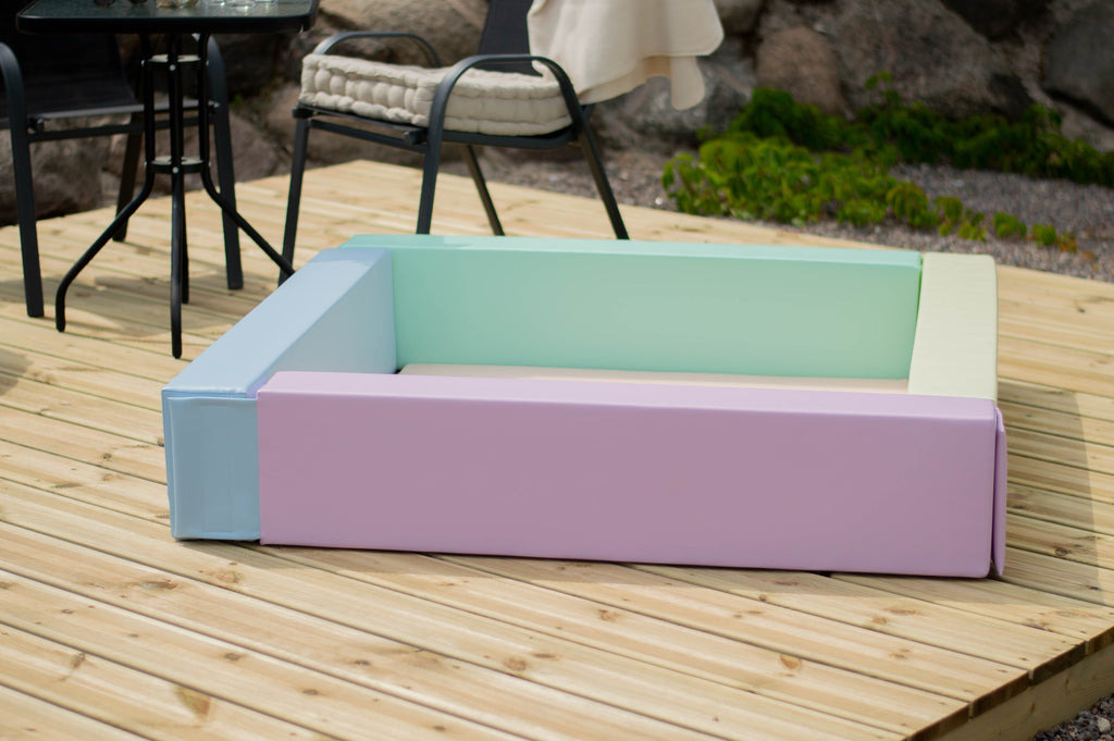 toddler laughing in a soft pastel ball pit during a playful indoor adventure