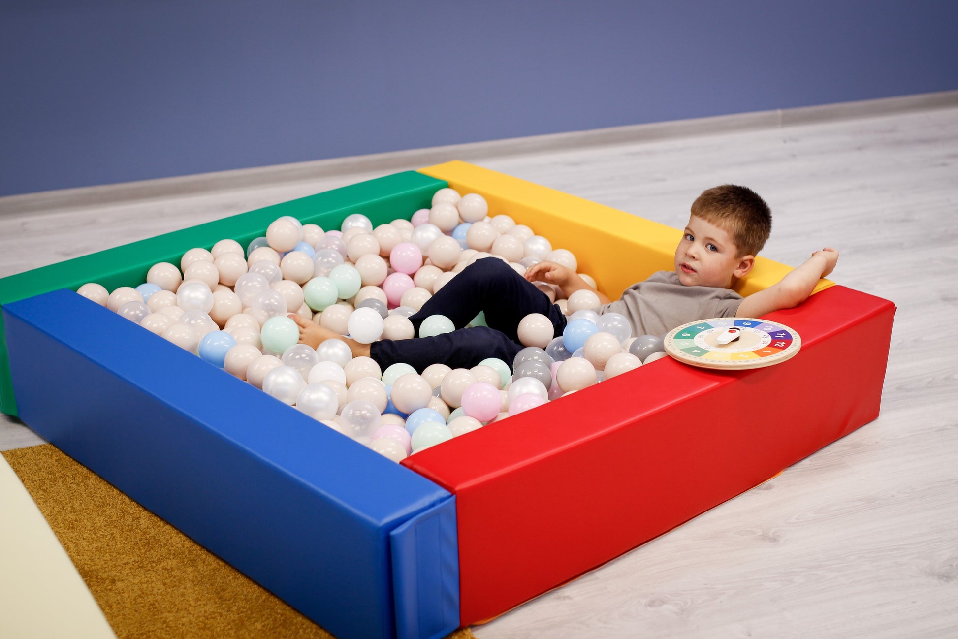 a toddler's hand reaching into a vibrant igloo-shaped ball pit filled with colorful sensory play balls