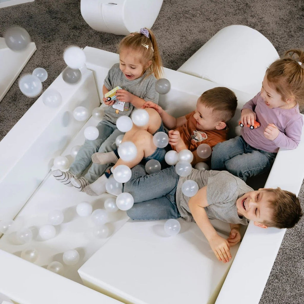 child laughing in a white iglu soft play ball pit during a backyard adventure