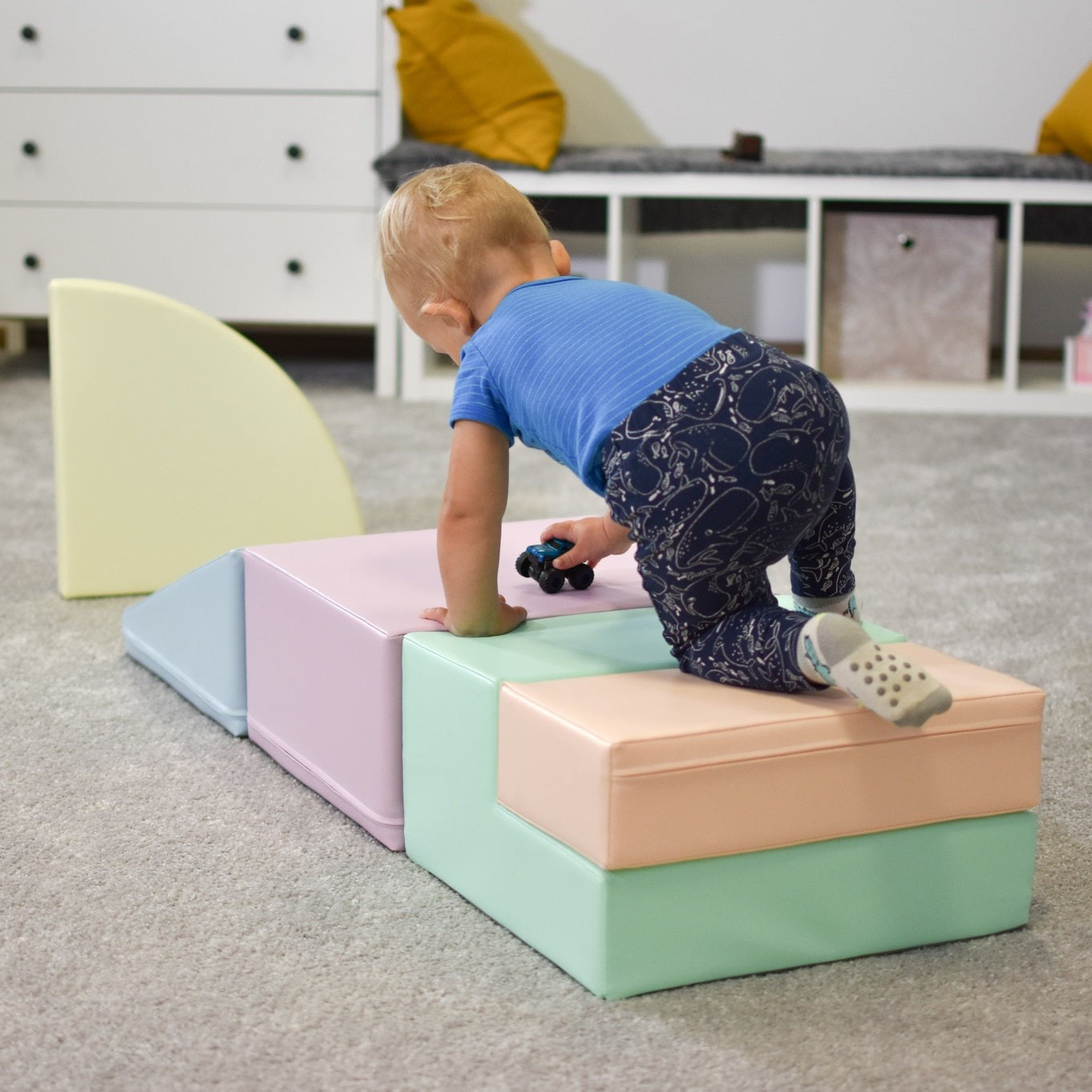 a toddler building a pastel foam climber in a sunlit playroom