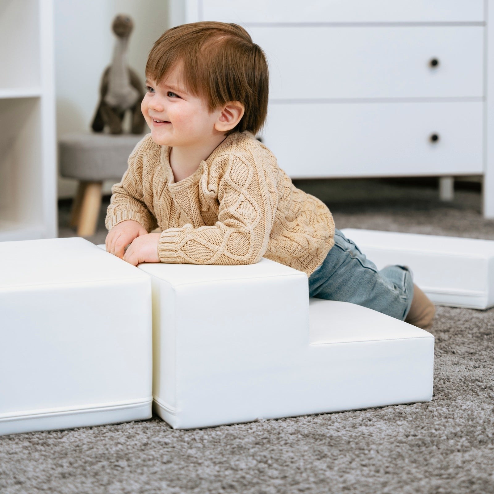 a toddler's hand reaching for the soft white corner climber foam block