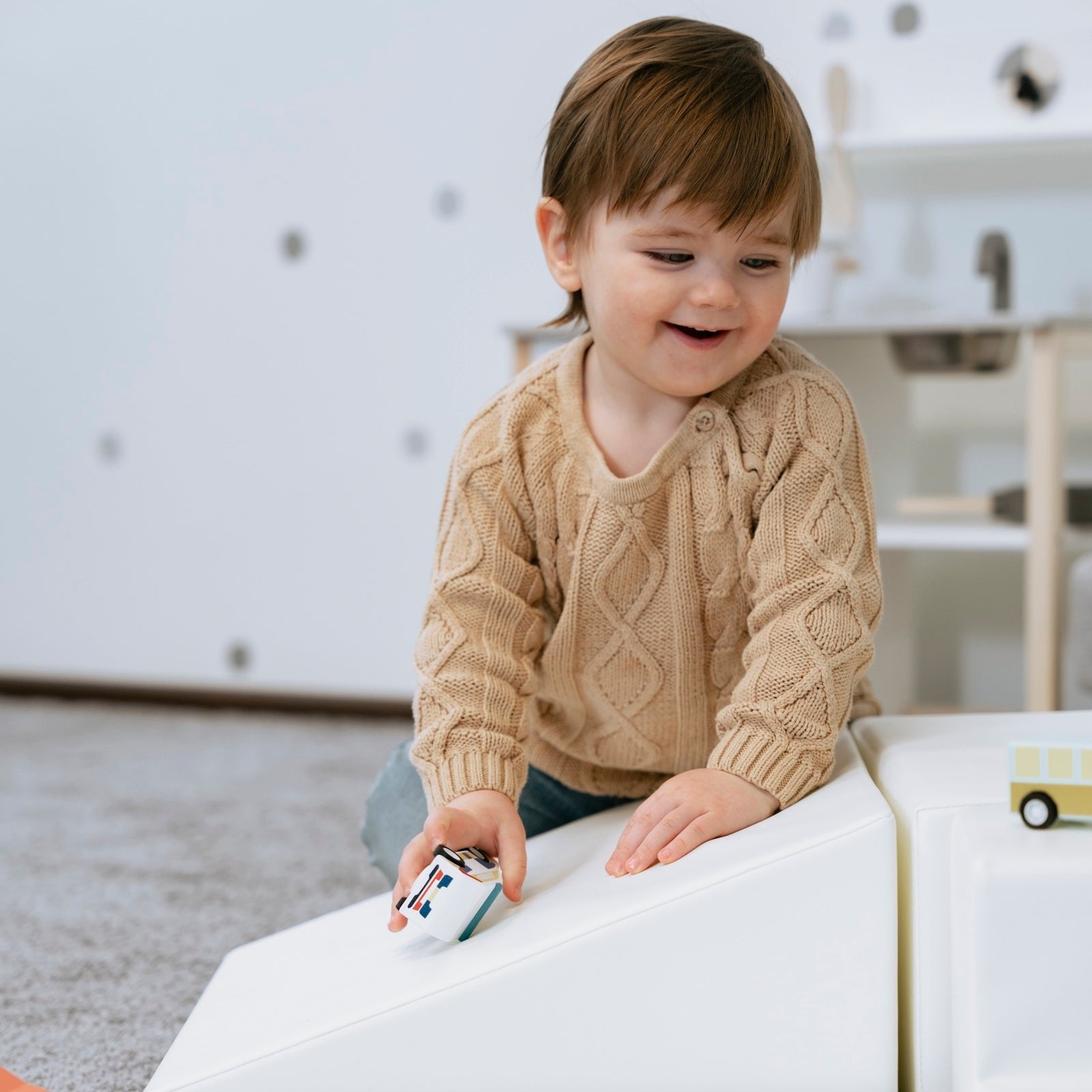 a toddler building a creative obstacle course with soft white foam blocks