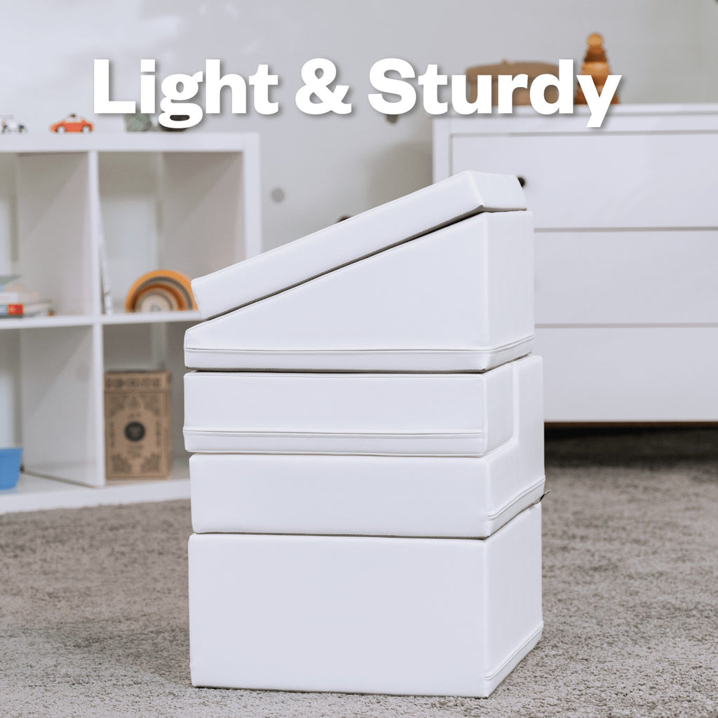a toddler climbing a white foam corner climber in a sunlit playroom