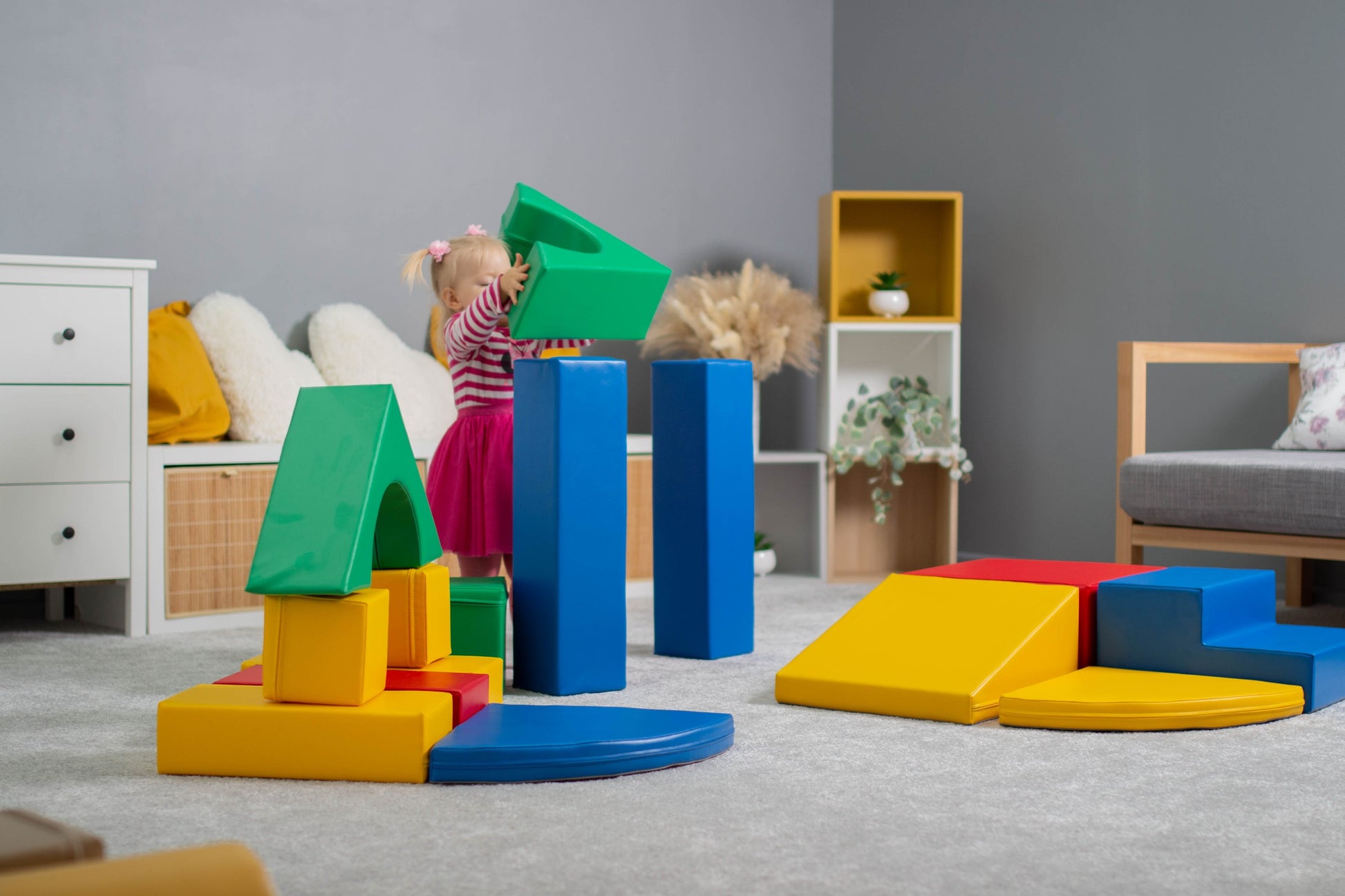a toddler giggling as they build a colorful iglu foam block tower