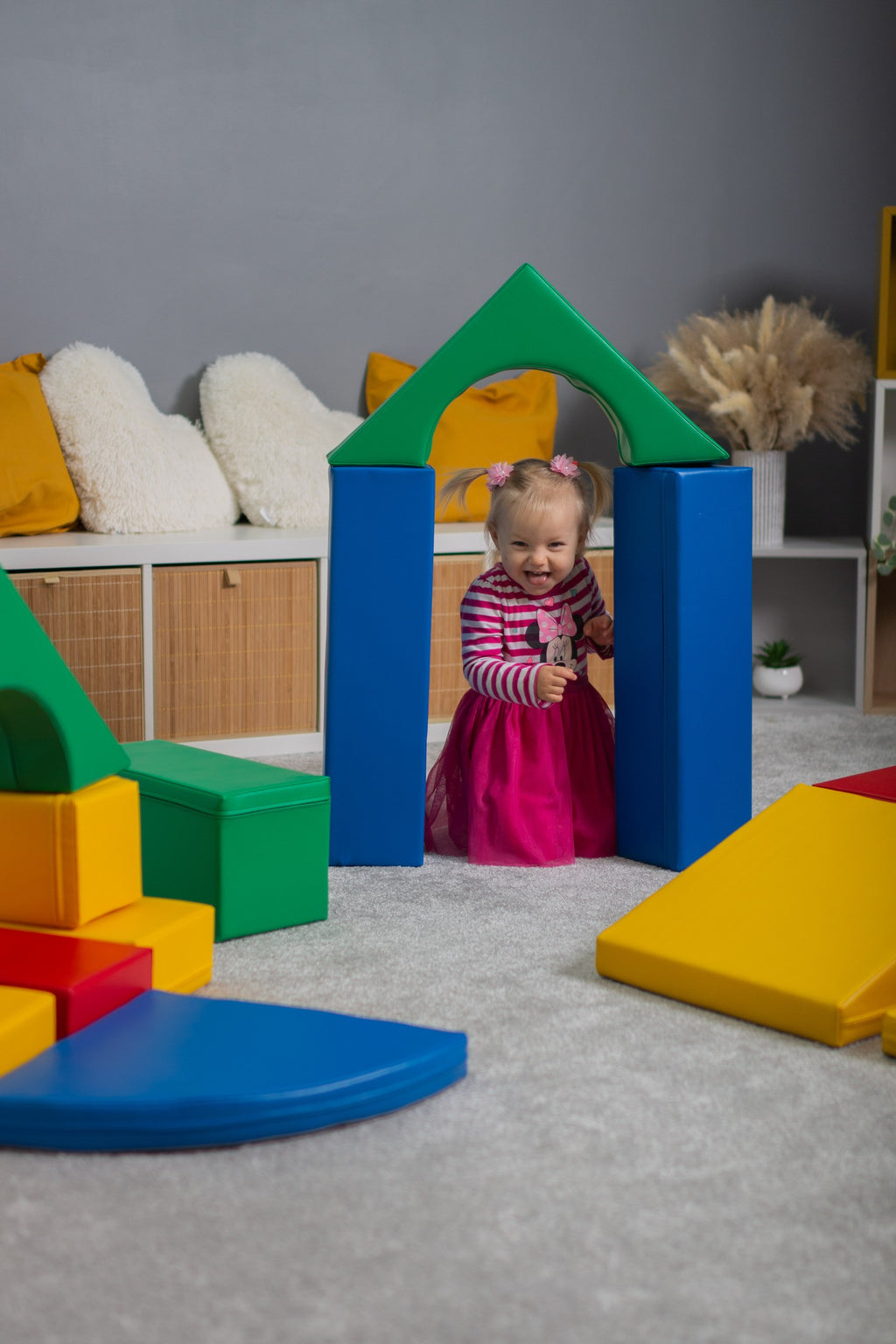 a child's hand reaching for a vibrant teal iglu foam block on a soft play mat