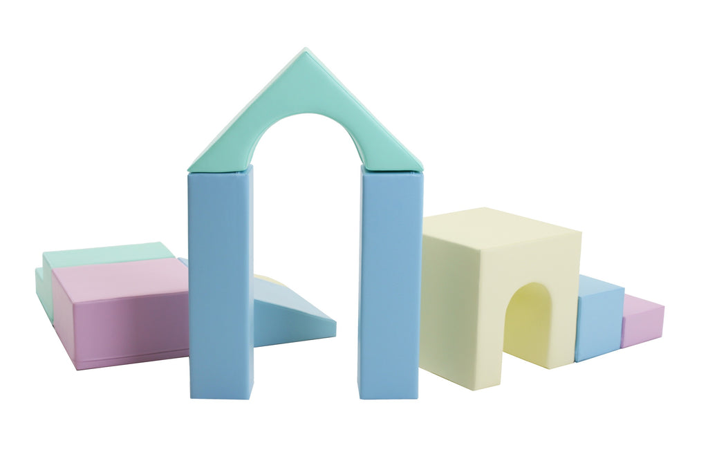 a child's hand stacking pastel iglu foam blocks on a soft play mat