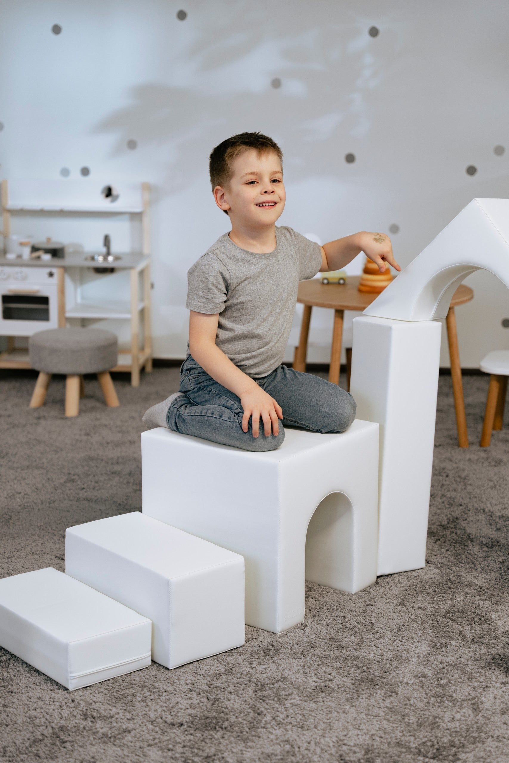 a child building a creative white iglu foam block castle in a sunlit playroom