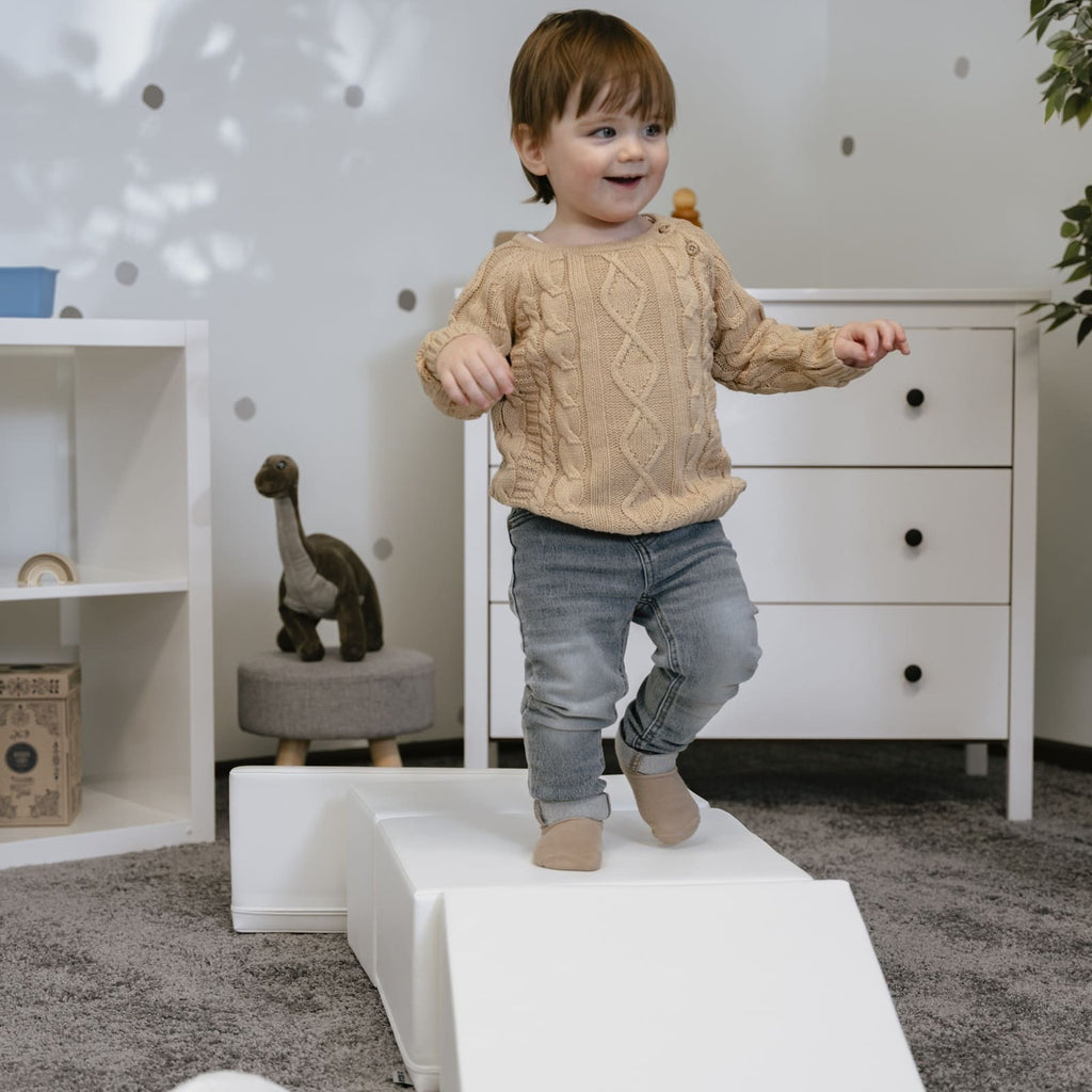 a child building a creative igloo fort with soft white foam blocks in a sunlit playroom