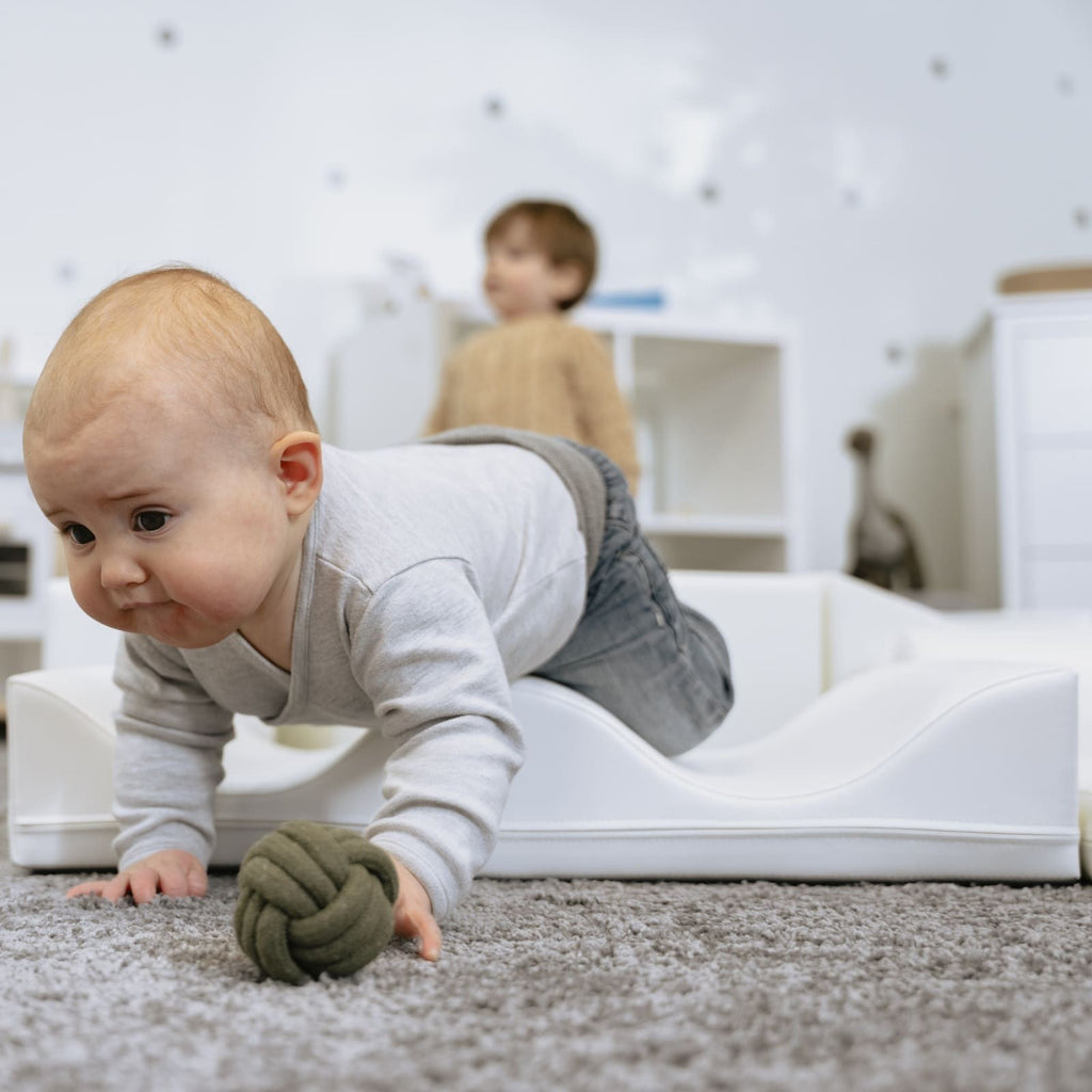child building a soft white foam block tower on a hardwood floor