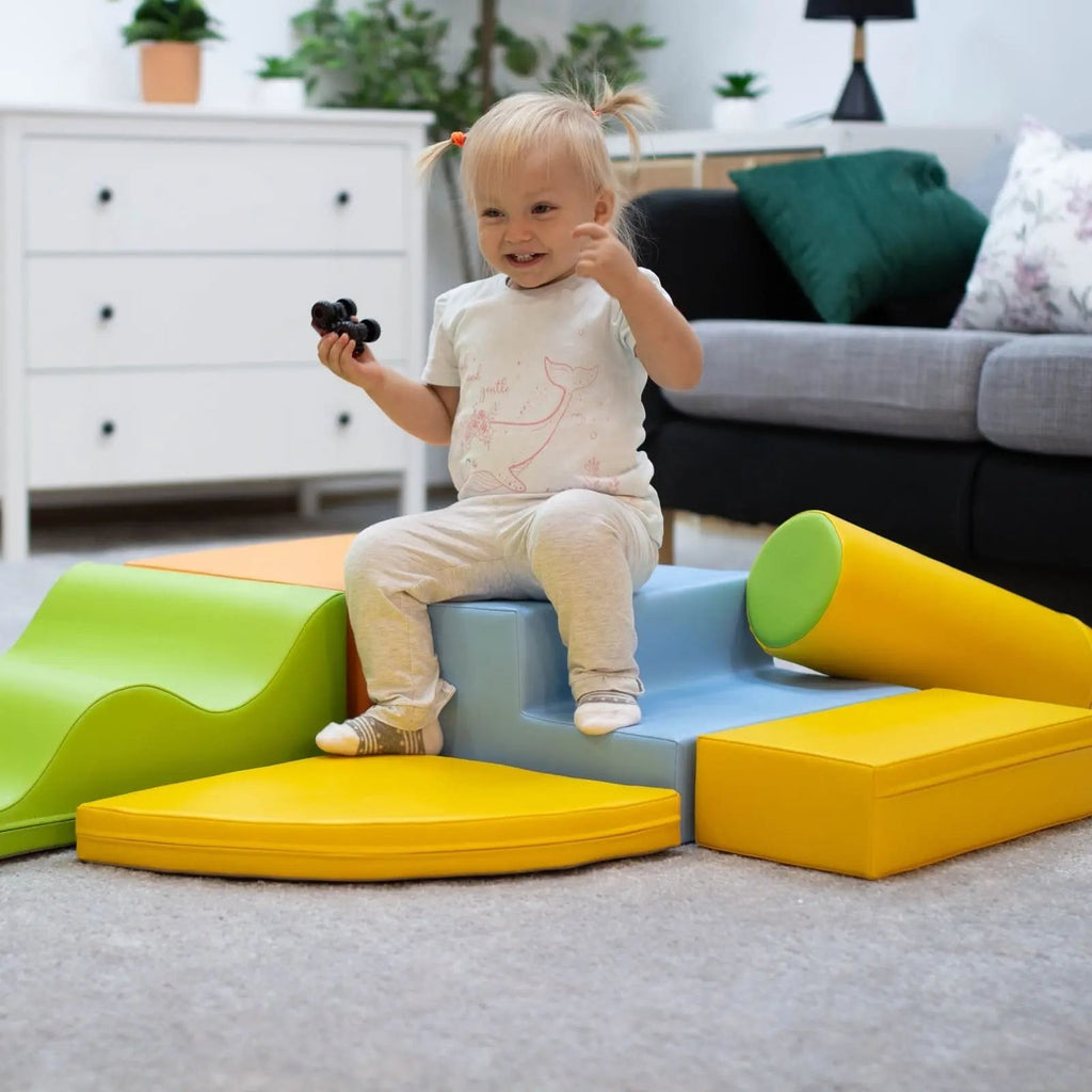 toddler laughing while building a colorful iglu foam block archway