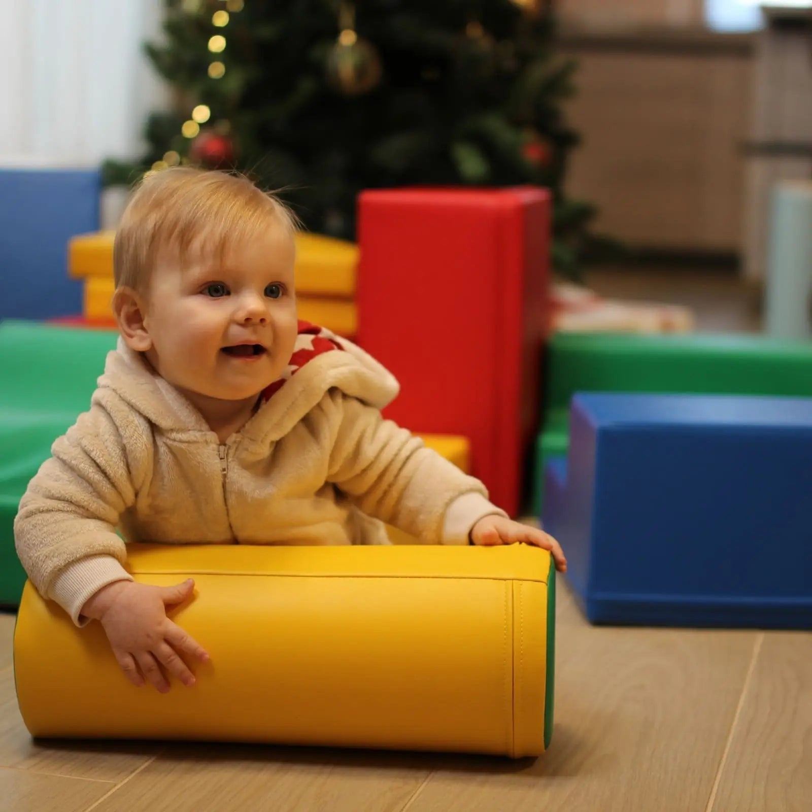 a toddler's hand stacking a vibrant iglu foam block in a sunlit playroom