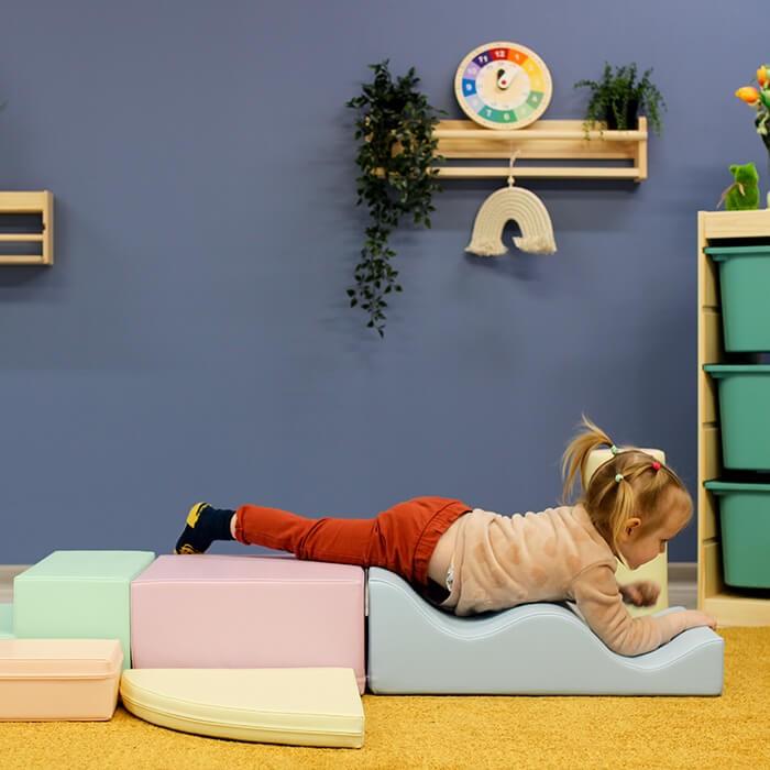 a toddler building a cozy pastel igloo fort with soft foam blocks