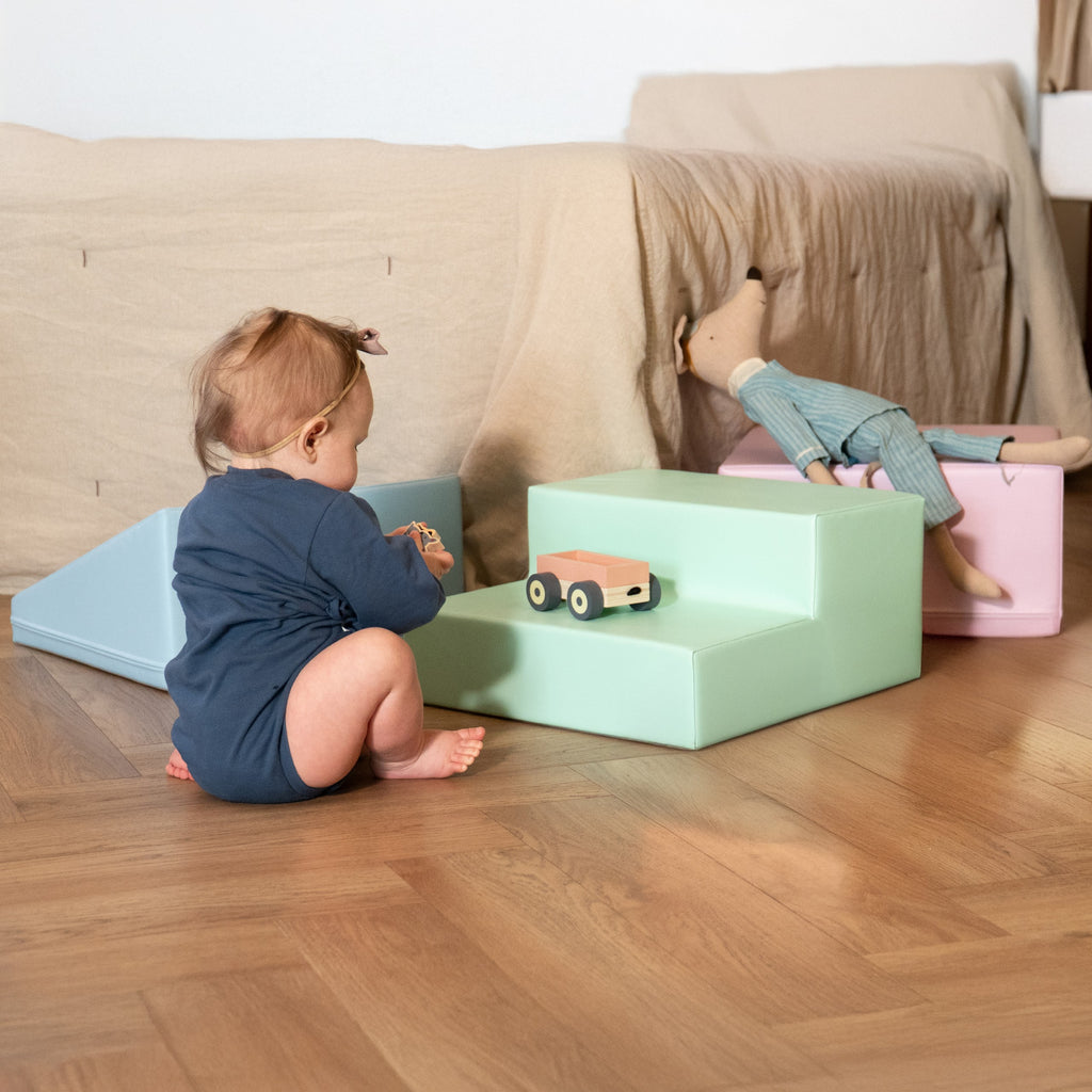 a toddler's joyful flop onto a pastel foam block during a playful climbing adventure