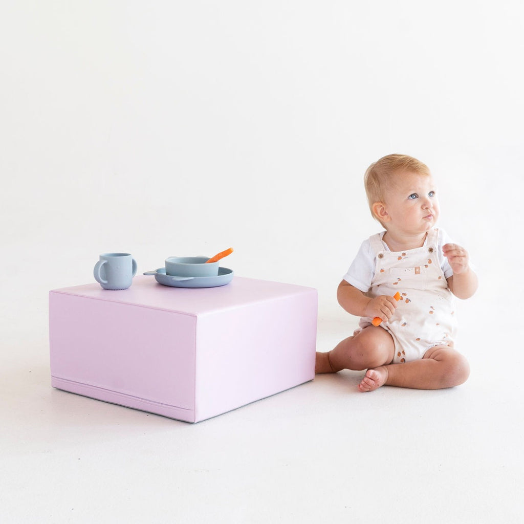 a toddler's hand exploring the soft, pastel slope of a foam climber block