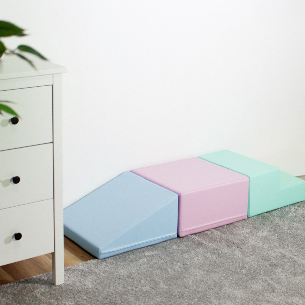 a toddler's hand touching a soft pastel foam block in warm morning light