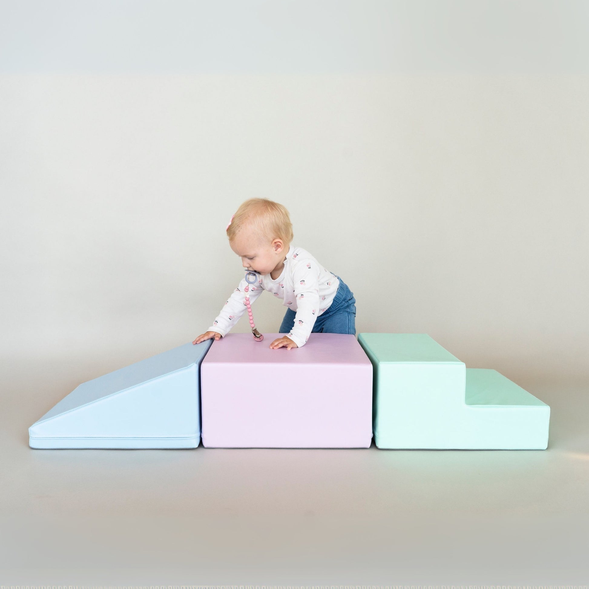 a bold toddler conquering a pastel foam block mountain in dramatic morning light