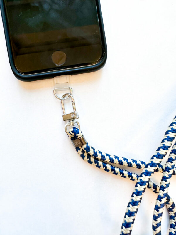 playful seik universal phone strap in sea edge blue, held by a hand on a sunny beach adventure