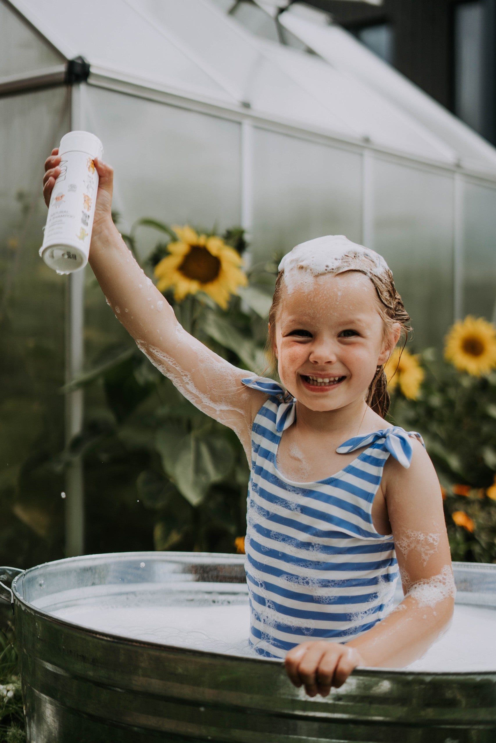 a playful burst of pear-scented purple shower foam in a child's hands