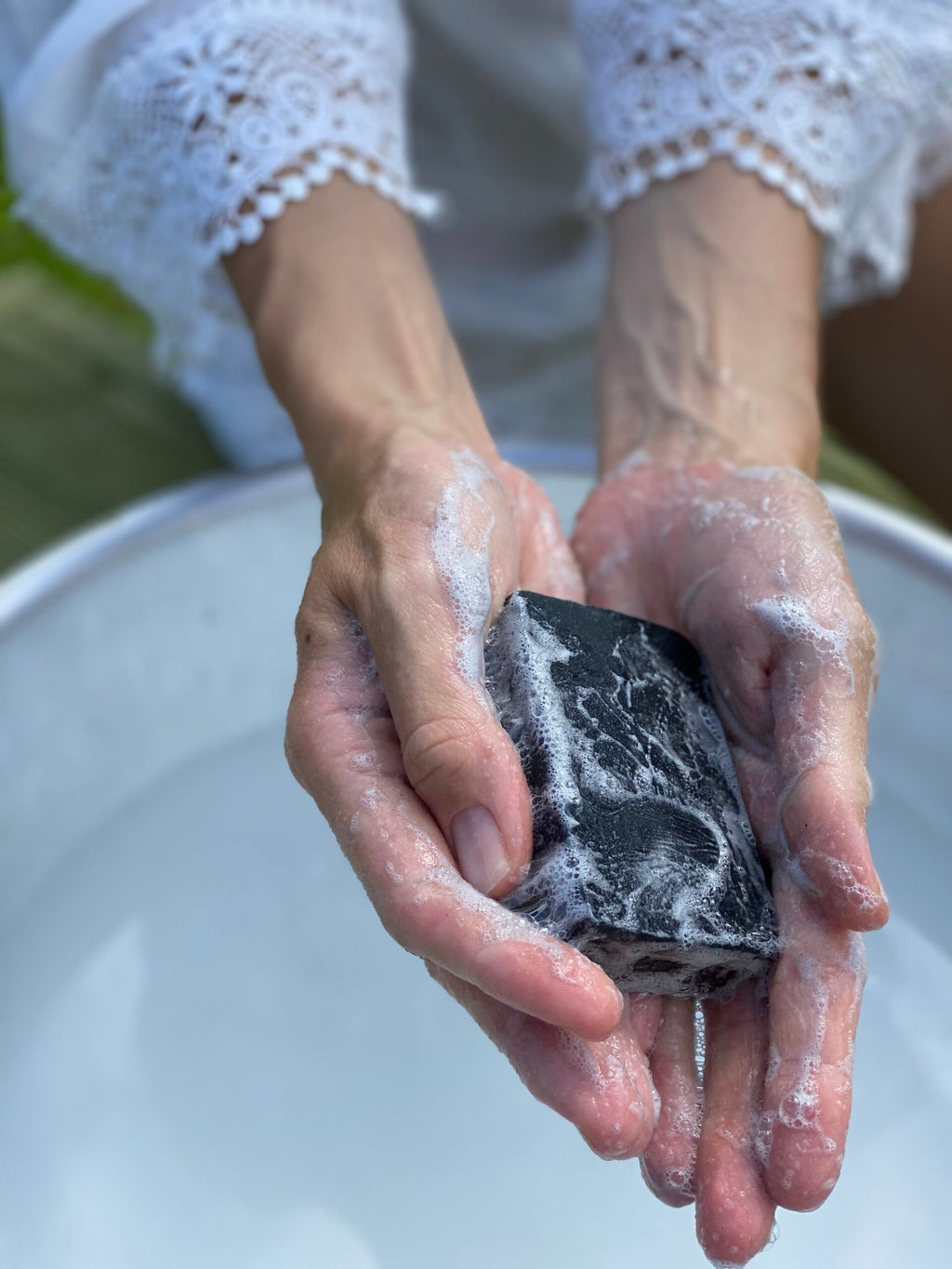 a playful close-up of the revitalizing charcoal and goat's milk facial bar with rich lather