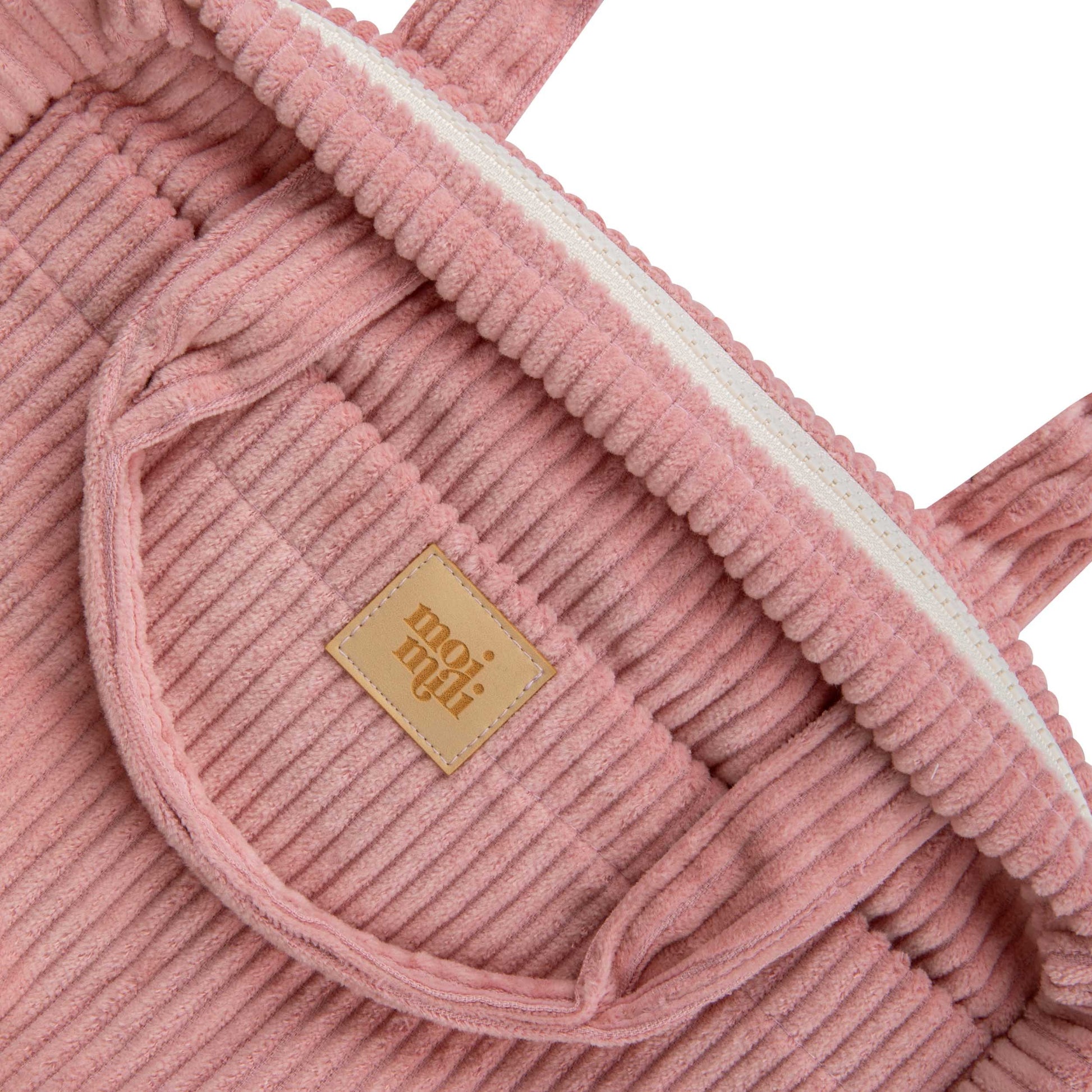 close-up of a chic baby pink cotton makeup bag on a sandy beach, showcasing its waterproof lining and outer pocket
