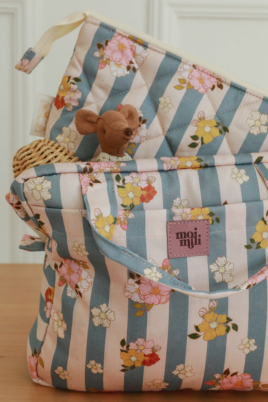 a functional blue striped cotton makeup bag set open on a table showing its inner and outer pockets for organization