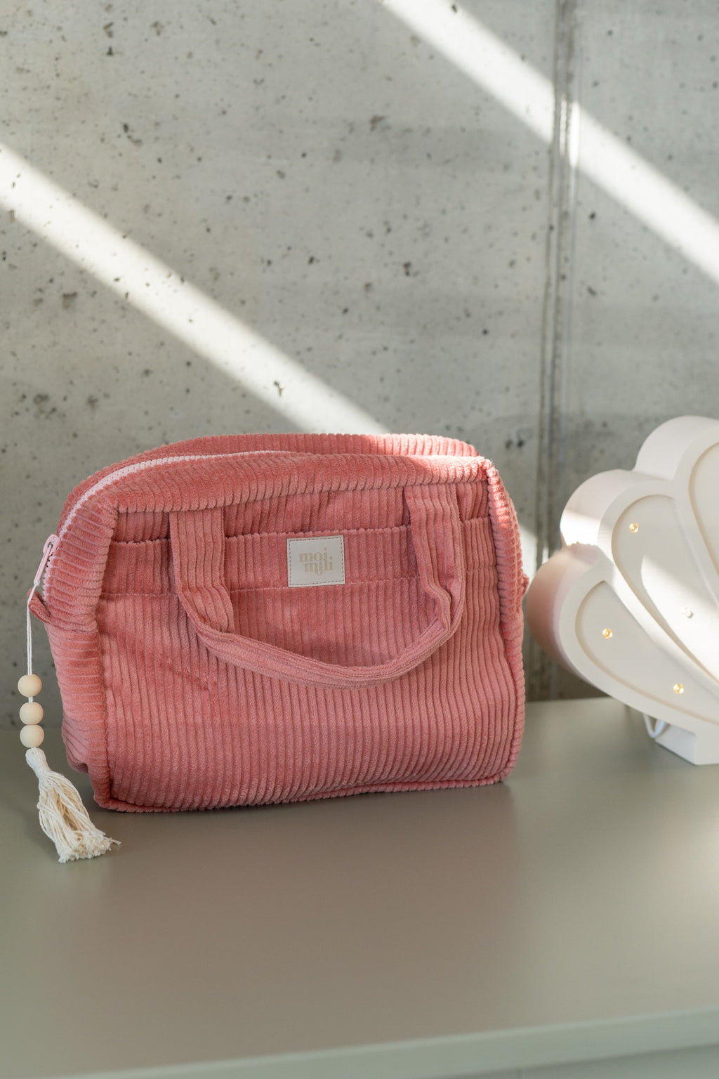 a playful close-up of the two chic coral makeup bags with their zippers open, spilling out colorful beauty essentials