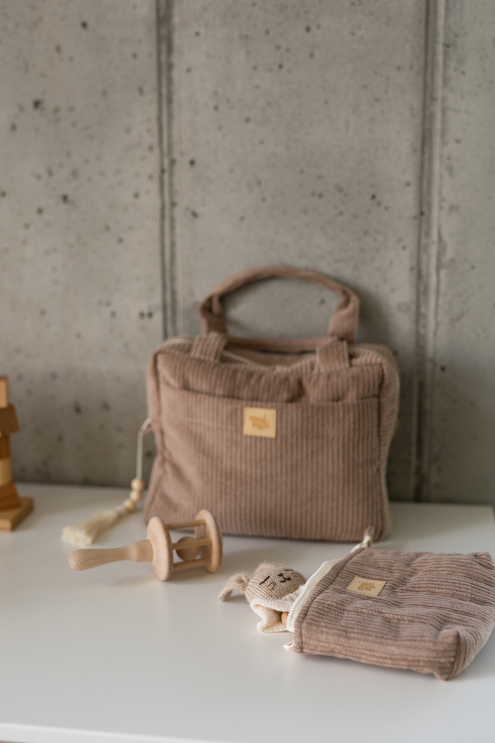 moi mili latte makeup bag set of two on a wooden table, showcasing its cotton texture and practical size for travel