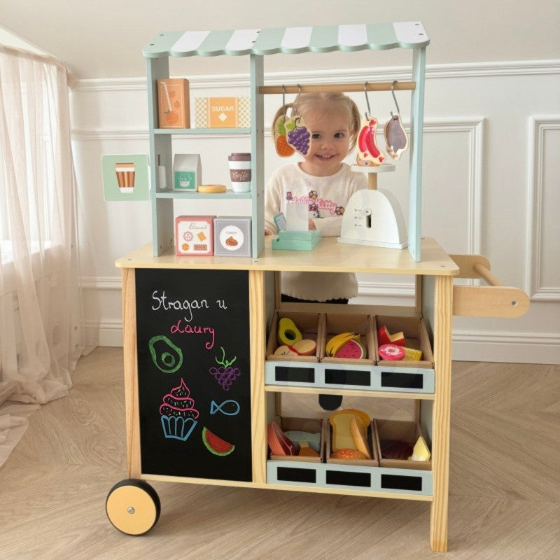 a child's hands carefully arranging wooden fruits on the food truck's scale during imaginative play
