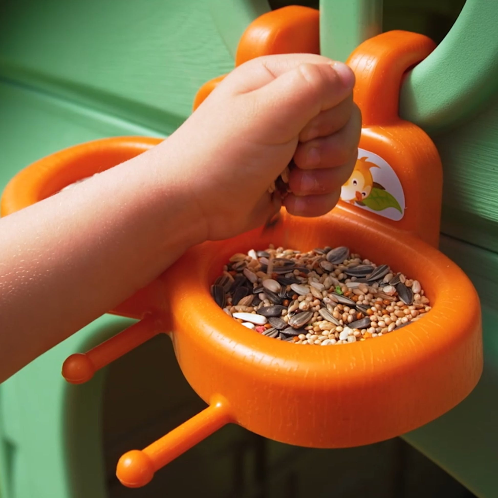 child tending to plants in a recycled playhouse garden with a blue recycling bin