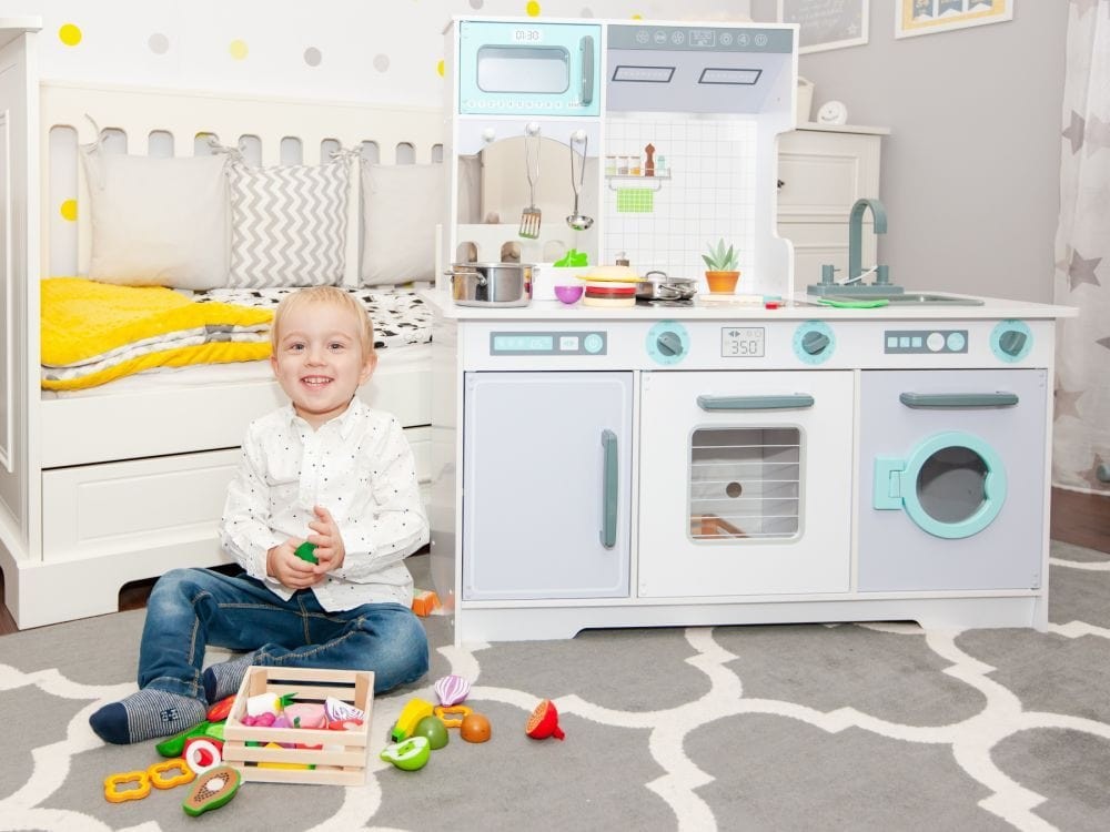 a soft-lit view of a child's wooden play kitchen, focusing on the cozy details of the sink and accessories