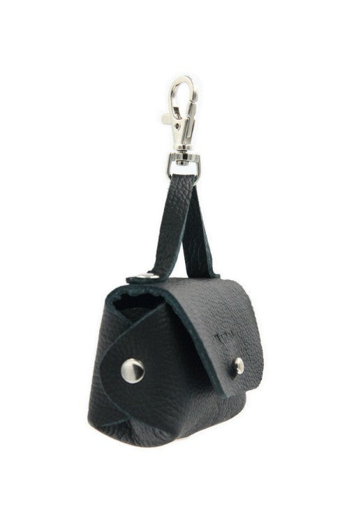 playful black leather dog bag dispenser attached to a leash on a sunny walk