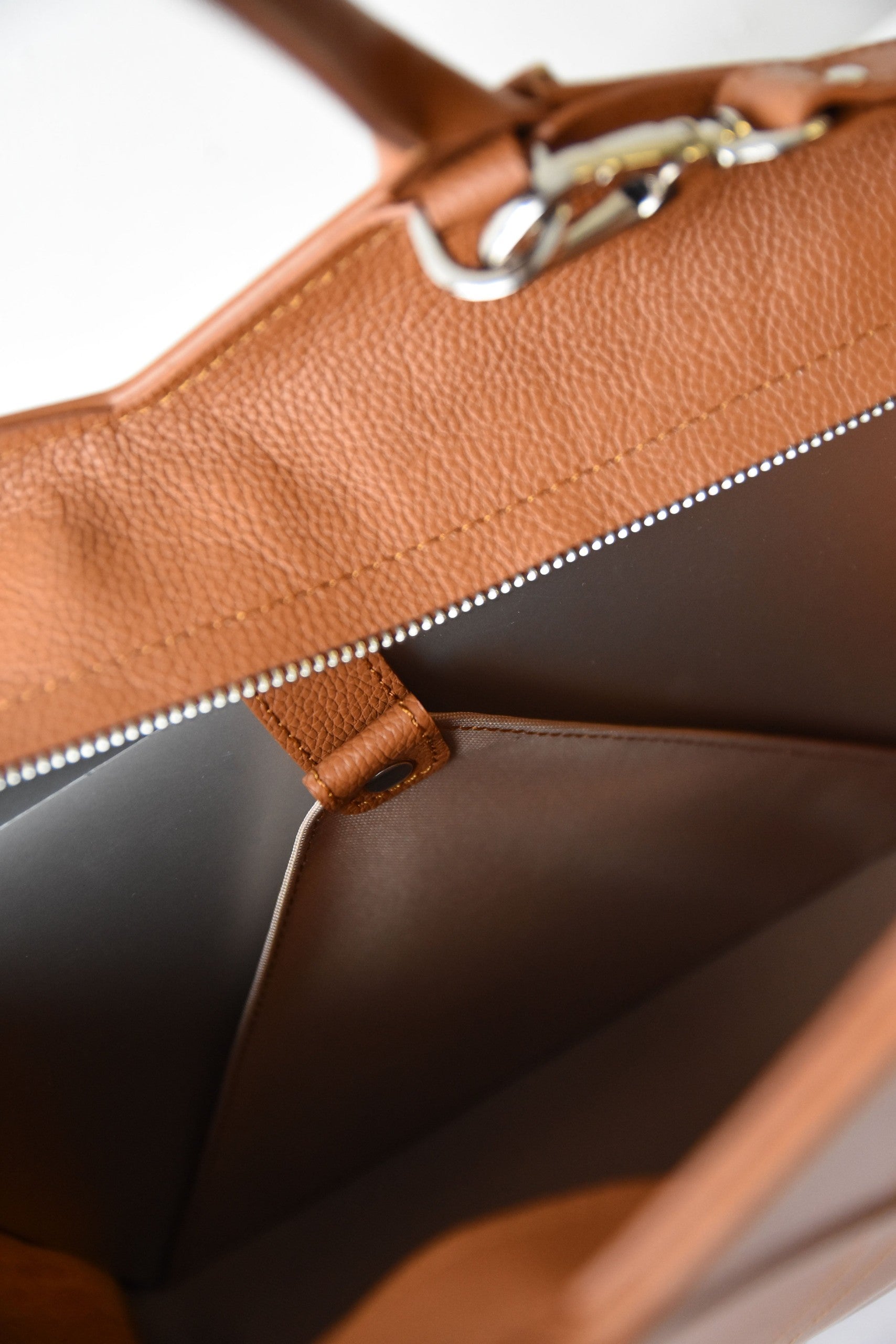 playful shot of a gerda retter leather tote bag held by a woman laughing in a sunlit park