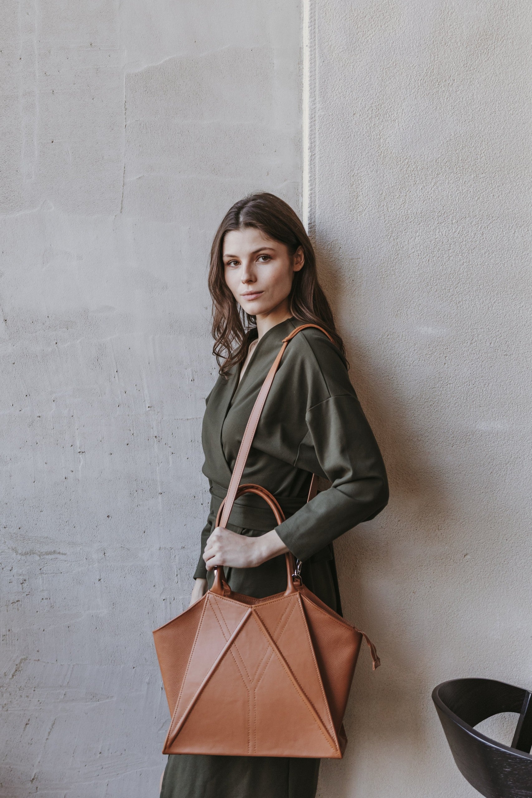 confident woman holding a bold gerda retter handmade leather tote bag in a studio shot