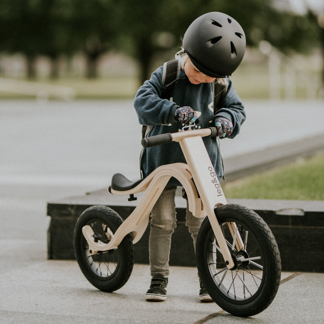 a functional close-up of the wooden balance bike's adjustable seat and inflatable tires