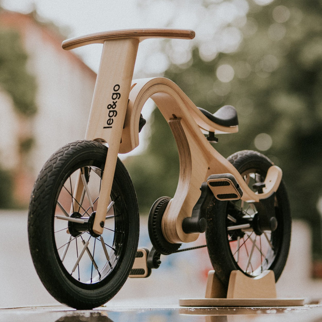 a child's hand on the wooden pedal of a lightweight balance bike conversion kit