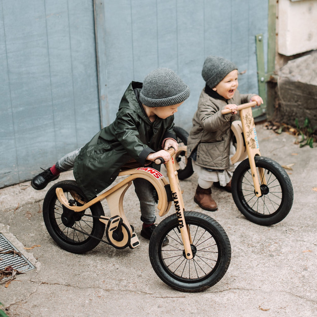 a child's hand confidently gripping the wooden handlebar of their newly converted pedal bike