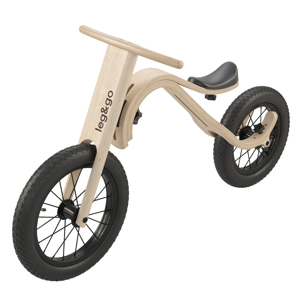 a soft-focus side view of the birch balance bike in a cozy nursery setting