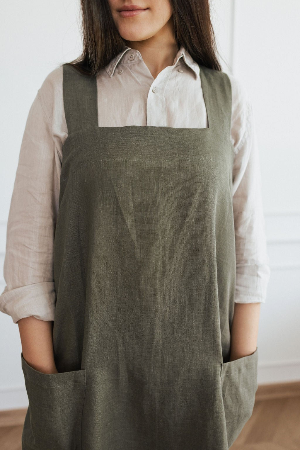 elegant linen apron with crossed back straps and side pockets, shown in a refined natural light setting